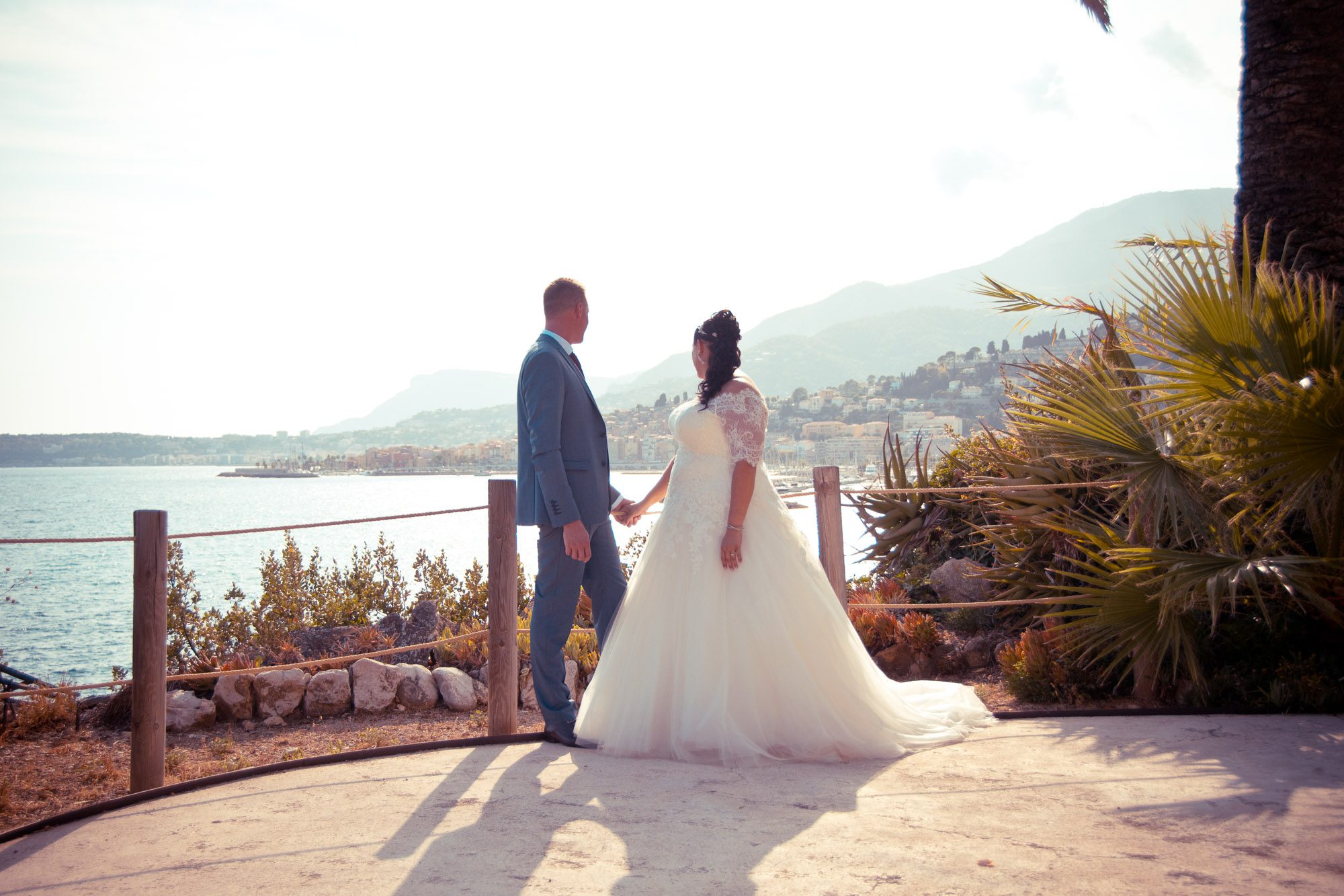 Moment d’intimité d’un couple de mariés à Menton, Villa Serena, avec vue panoramique sur la baie méditerranéenne aux couleurs chaudes et dorées