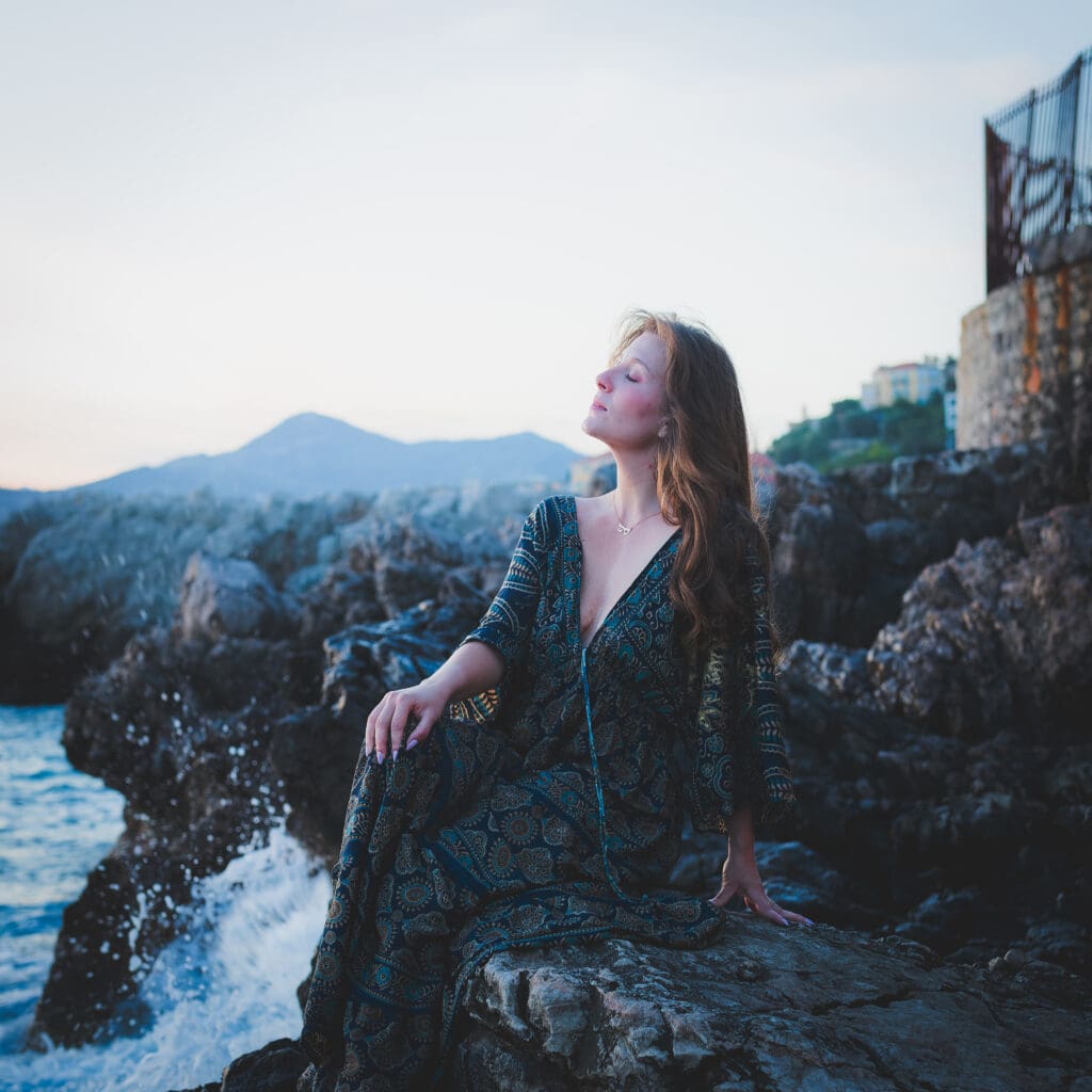 Portrait artistique au bord de mer à Nice, sur les rochers, à l’heure bleue juste après le coucher du soleil.