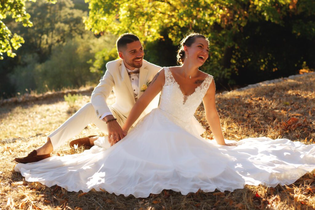 Un couple échange un sourire complice lors de leur union en extérieur à Grasse, capturés dans une ambiance naturelle et lumineuse. Relevant la beauté de la robe de la mariée.