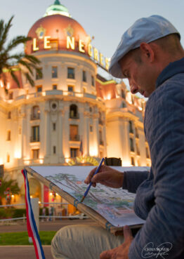 Peintre en train de dessiner l’hôtel Negresco illuminé de en début de soirée à Nice sur la Promenade des Anglais
