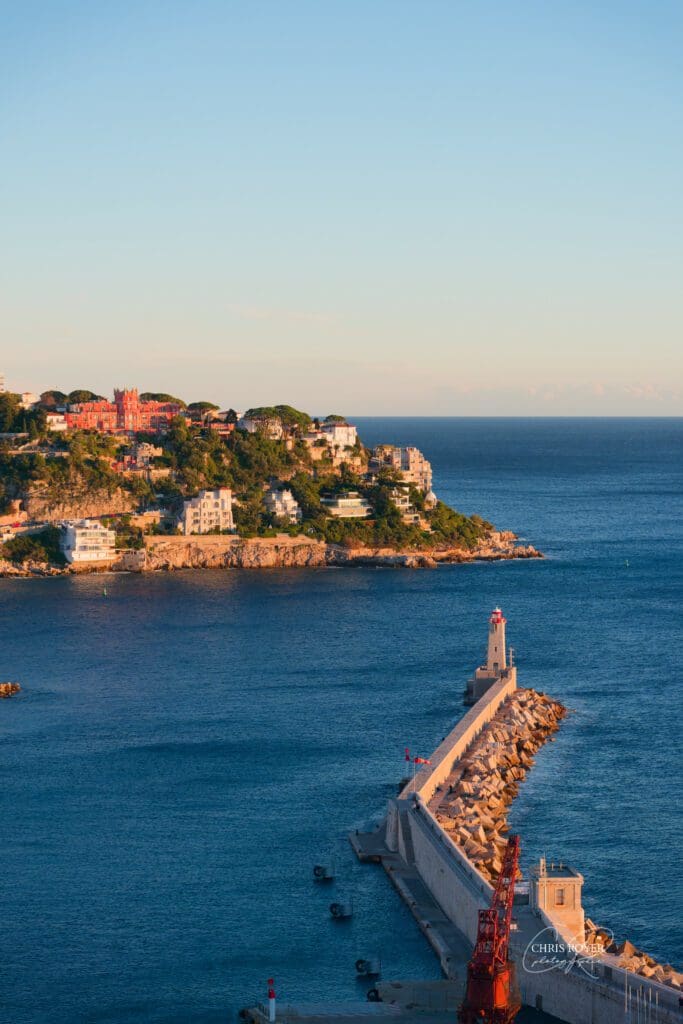 Vue panoramique sur le phare du port de Nice et les villas depuis la colline du château au coucher de soleil, depuis le belvédère dominant la Méditerranée.