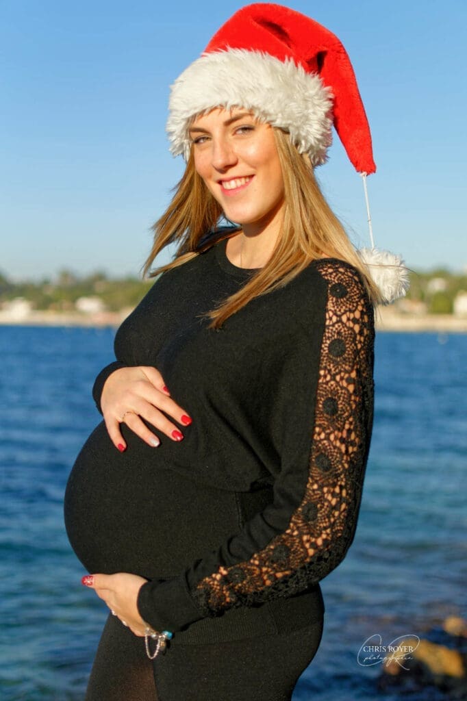 Femme enceinte posant en extérieur à Antibes, entourée de verdure et de lumière naturelle douce, illustrant un shooting photo grossesse dans les Alpes-Maritimes par Chris Royer Photographie