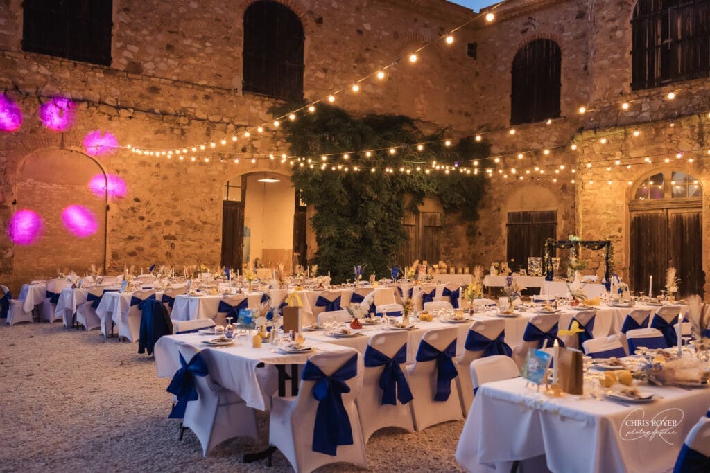 Dîner de mariage sous les guirlandes dans la cour en pierre du Domaine du Viet Dîner de mariage sous les guirlandes dans la cour en pierre du Domaine du Viet